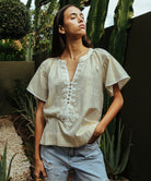 A model wearing a Rose and Rose Upminster gold top with white passementerie decoration.