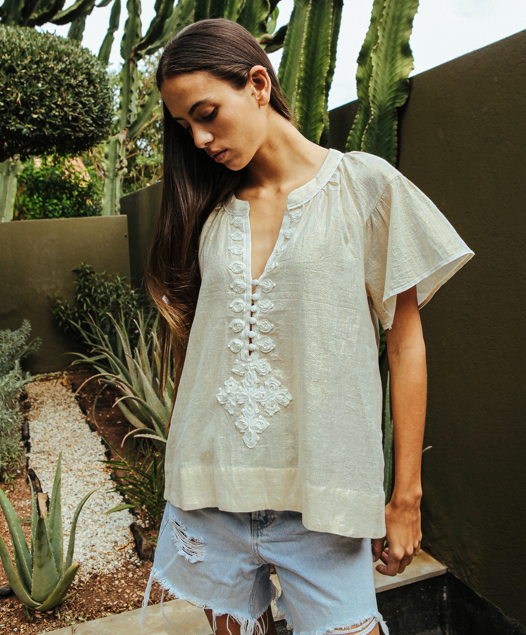 A model wearing a Rose and Rose Upminster gold top with white passementerie decoration.