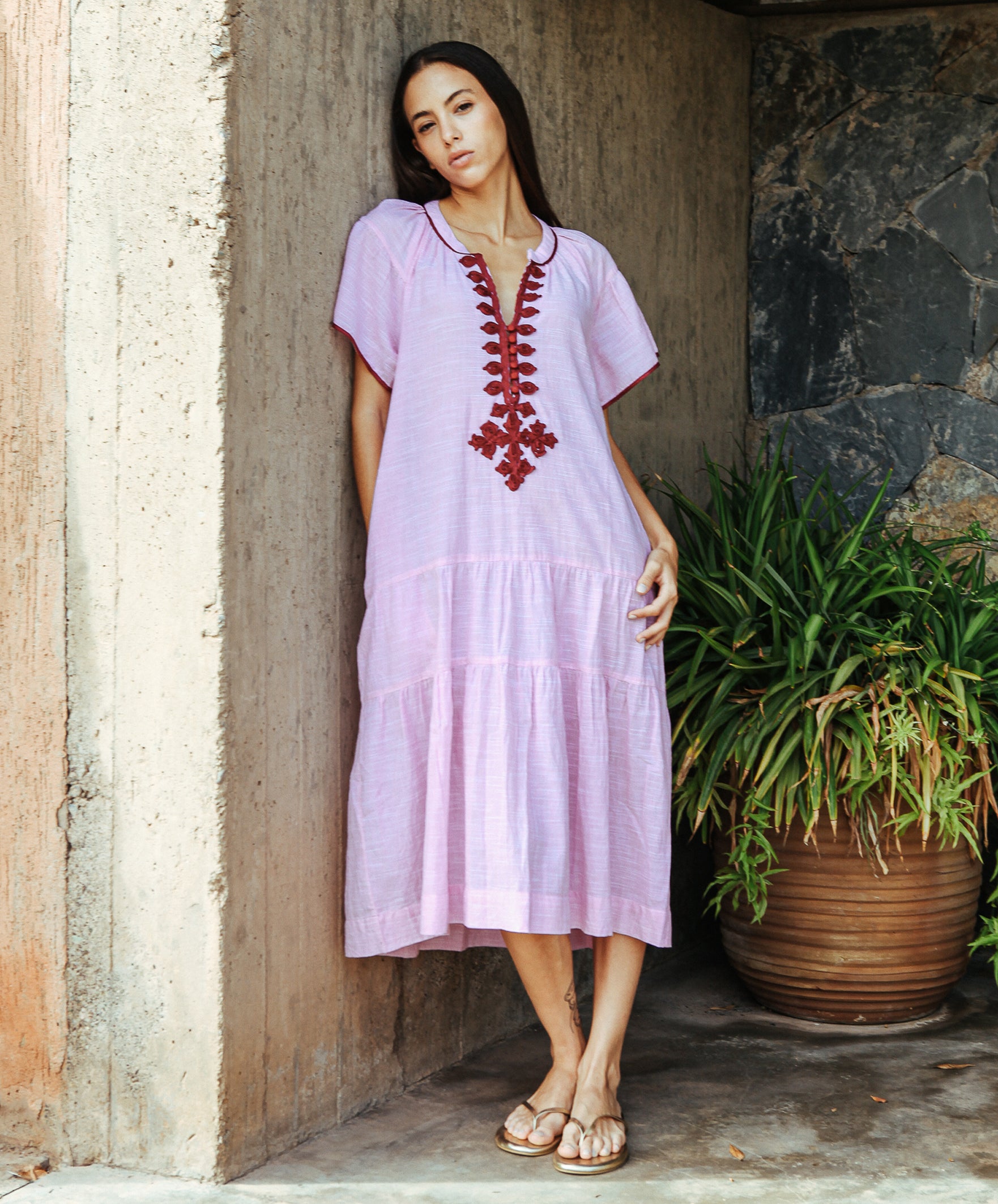 A model wearing a Rose and Rose Uxbridge dress in pink with berry passementerie decoration.