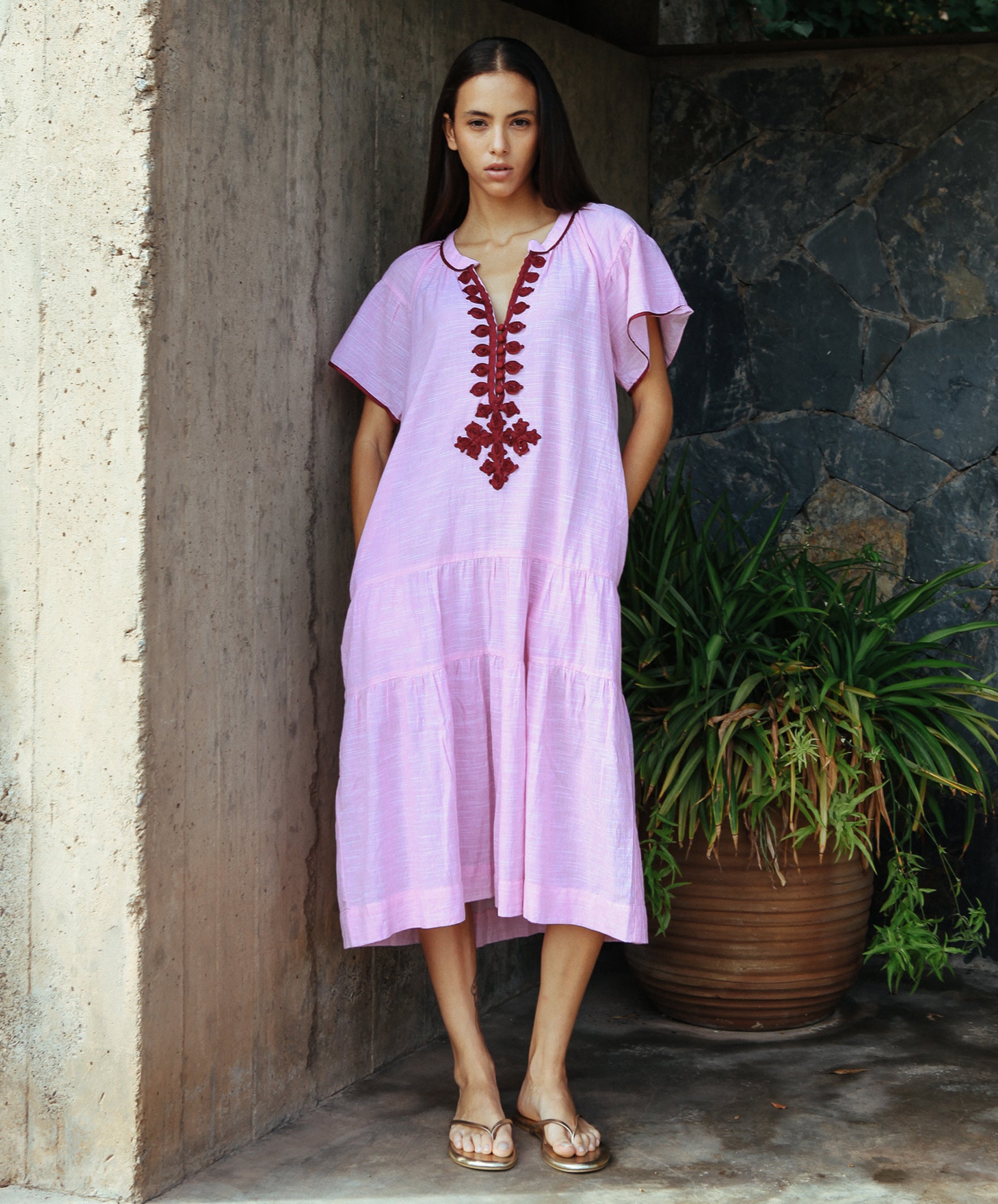 A model wearing a Rose and Rose Uxbridge dress in pink with berry passementerie decoration.