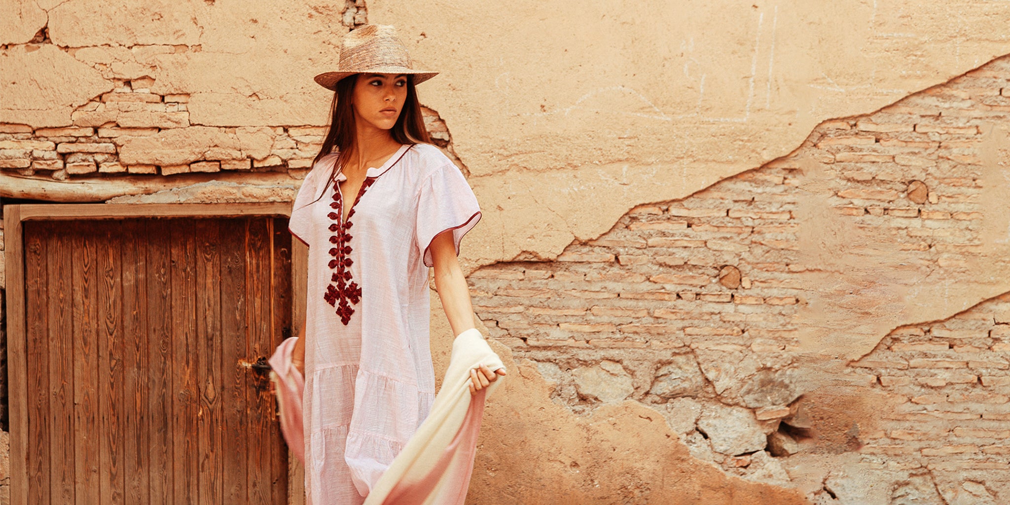 A model wearing a Rose and Rose pink Uxbridge dress, straw hat and summer wrap scarf.