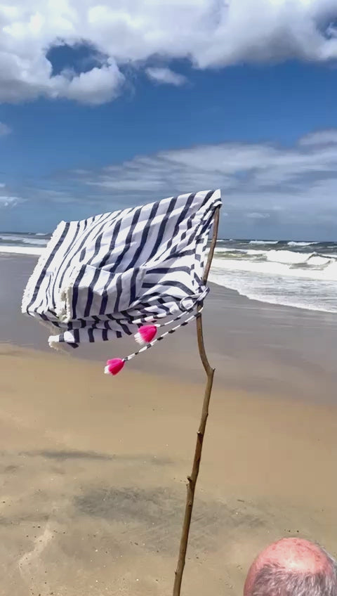A beach scene with a flag, made from a Rose and Rose kaftan, flapping in the wind.