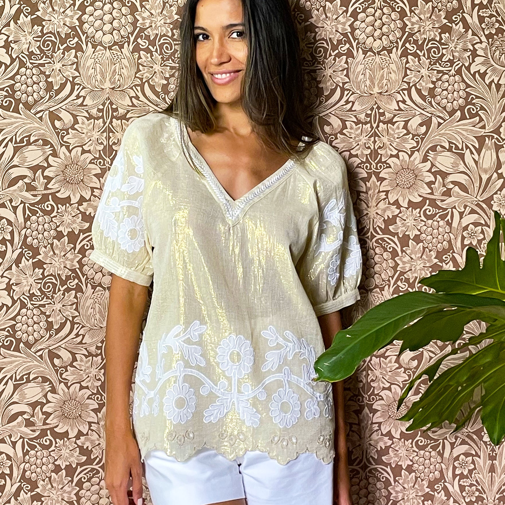 A model wearing a Rose and Rose gold lurex top with white appliqué and white shorts. 
