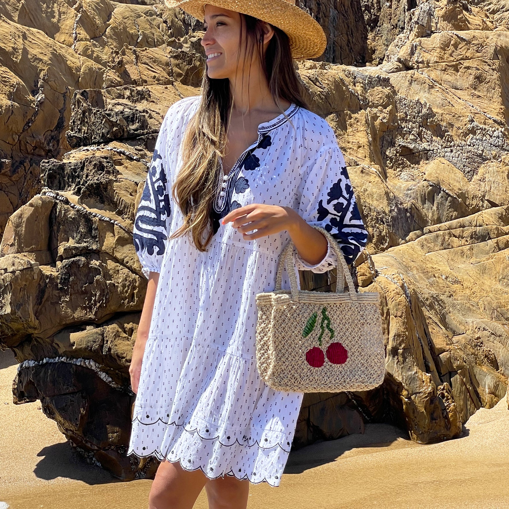 A model on the beach wearing a Rose and Rose Agrigento appliqué embroidered dress. 
