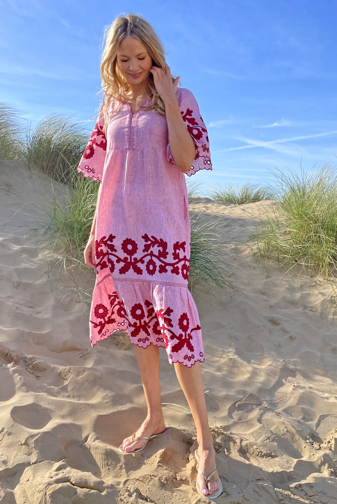 A model stood in sand dunes wearing a Rose and Rose red striped linen Agrigento dress.