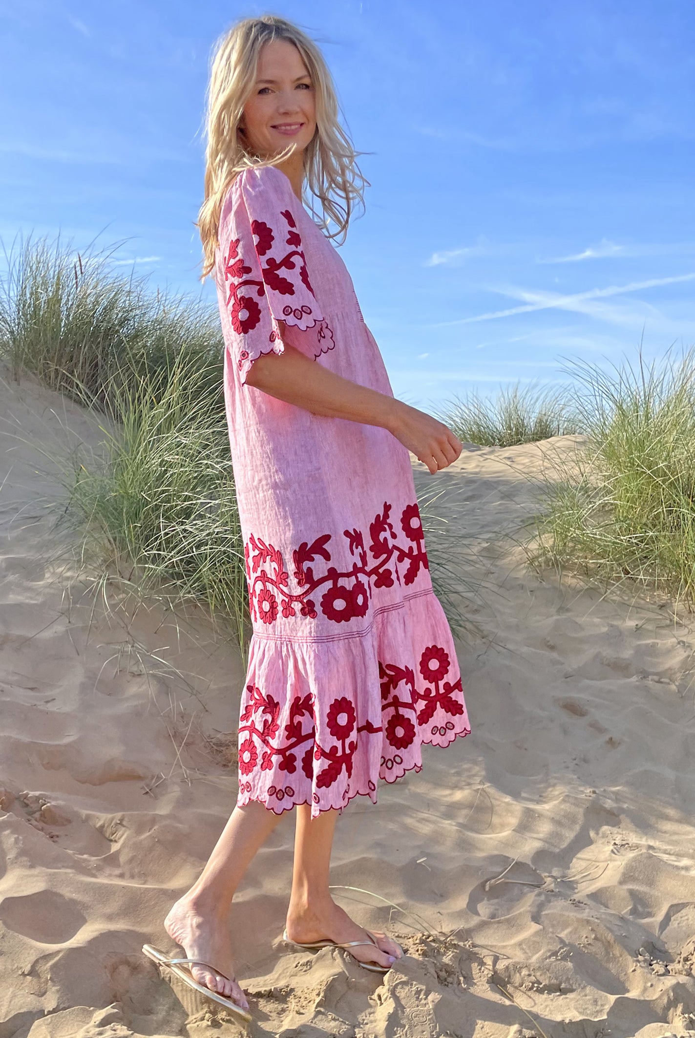 A model stood in sand dunes wearing a Rose and Rose red striped linen Agrigento dress. 