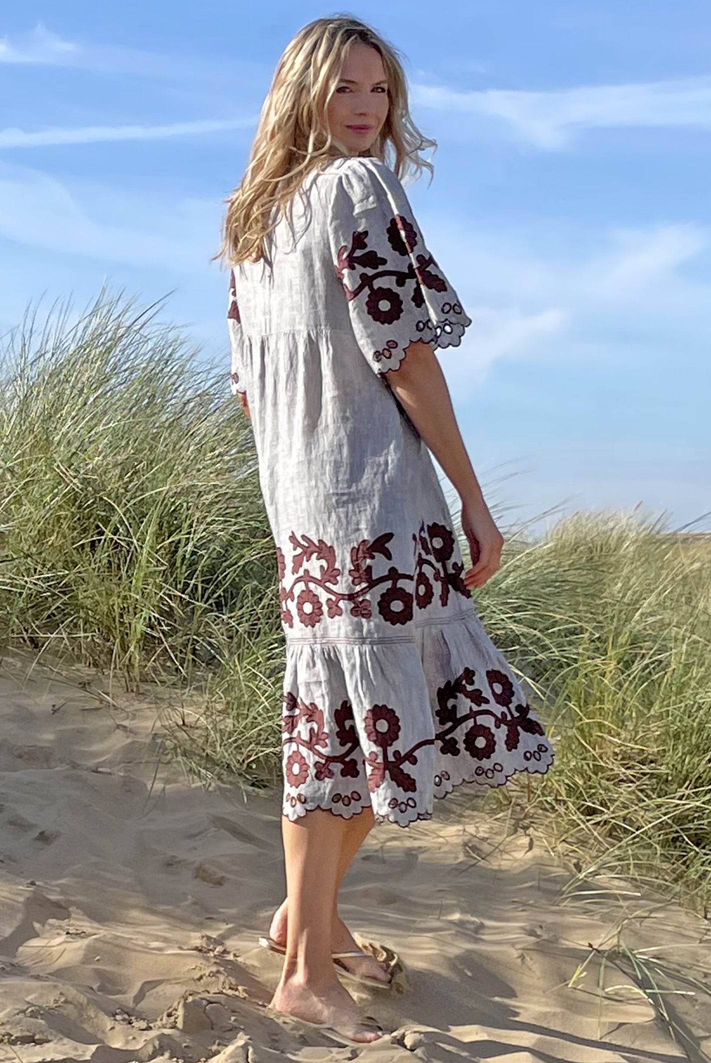 Back view of model stood in sand dunes wearing a Rose and Rose striped linen Agrigento dress.