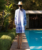 Back view of a woman wearing the Alder blue floral embroidered dress stood next to a pool.