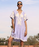 Woman wearing a striped blue Amaranta dress with white tape decoration with sunglasses against a desert background