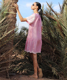 Woman in a red striped Amaranta dress standing among palm trees