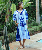 A model wearing a Rose and Rose Amersham cotton dress in white with cobalt appliqué decoration. 