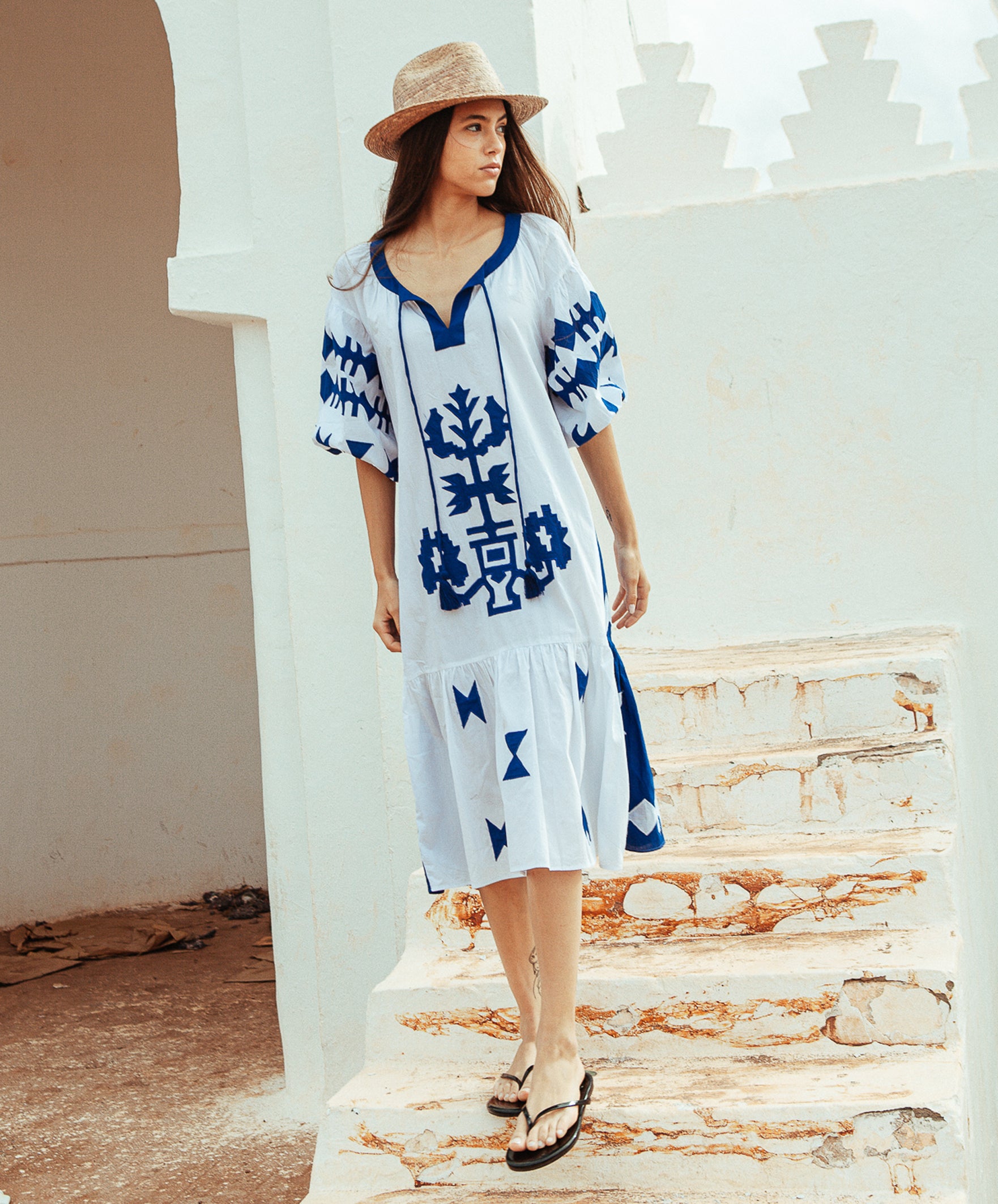 A model wearing a Rose and Rose Amersham cotton dress in white with cobalt appliqué decoration. 