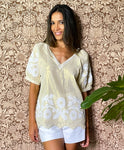 A model stood in front of floral wallpaper wearing the Rose and Rose gold lurex Anacapri top with white applique. 