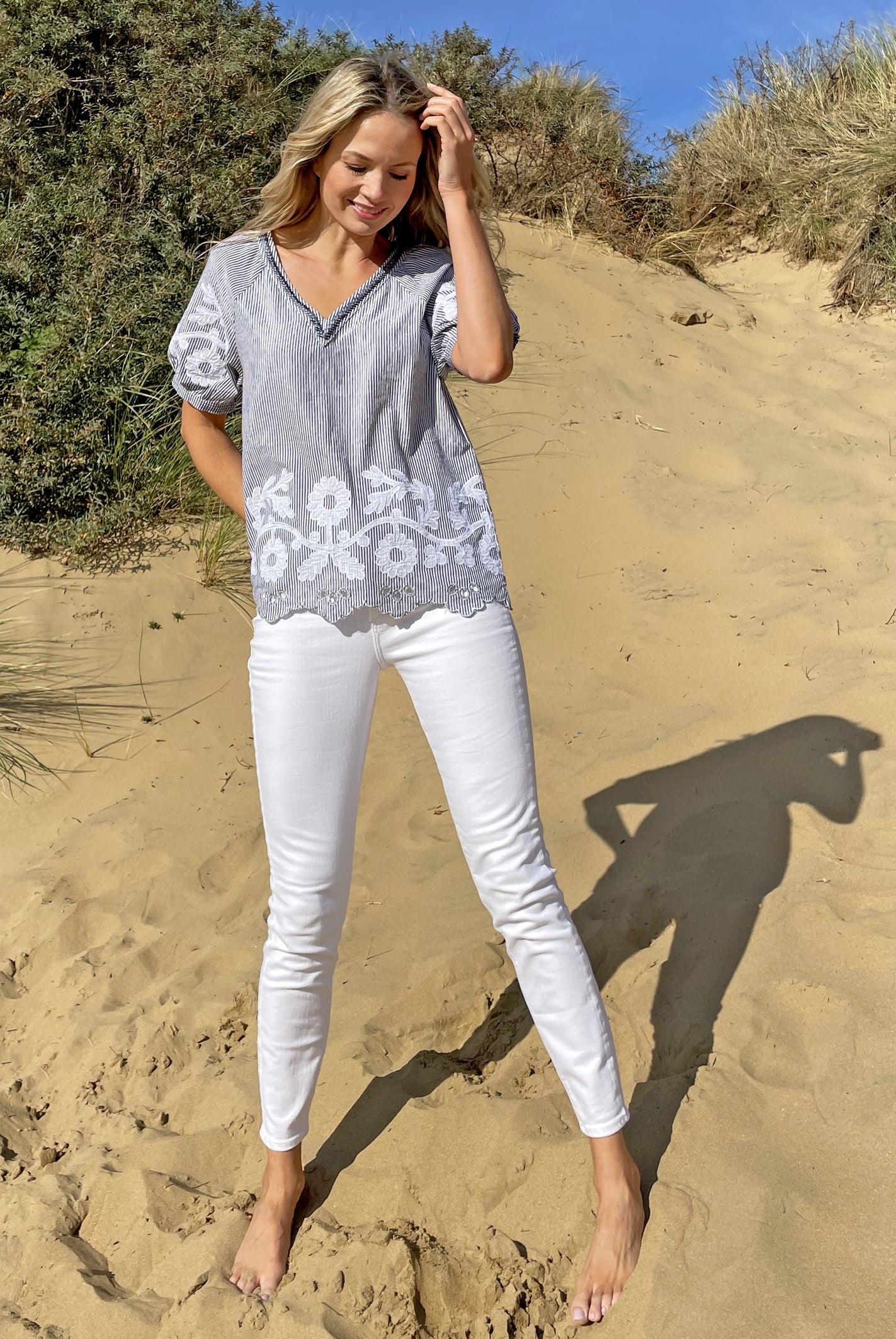  A model stood in sand dunes wearing a Rose and Rose striped cotton Anacapri top and white jeans.