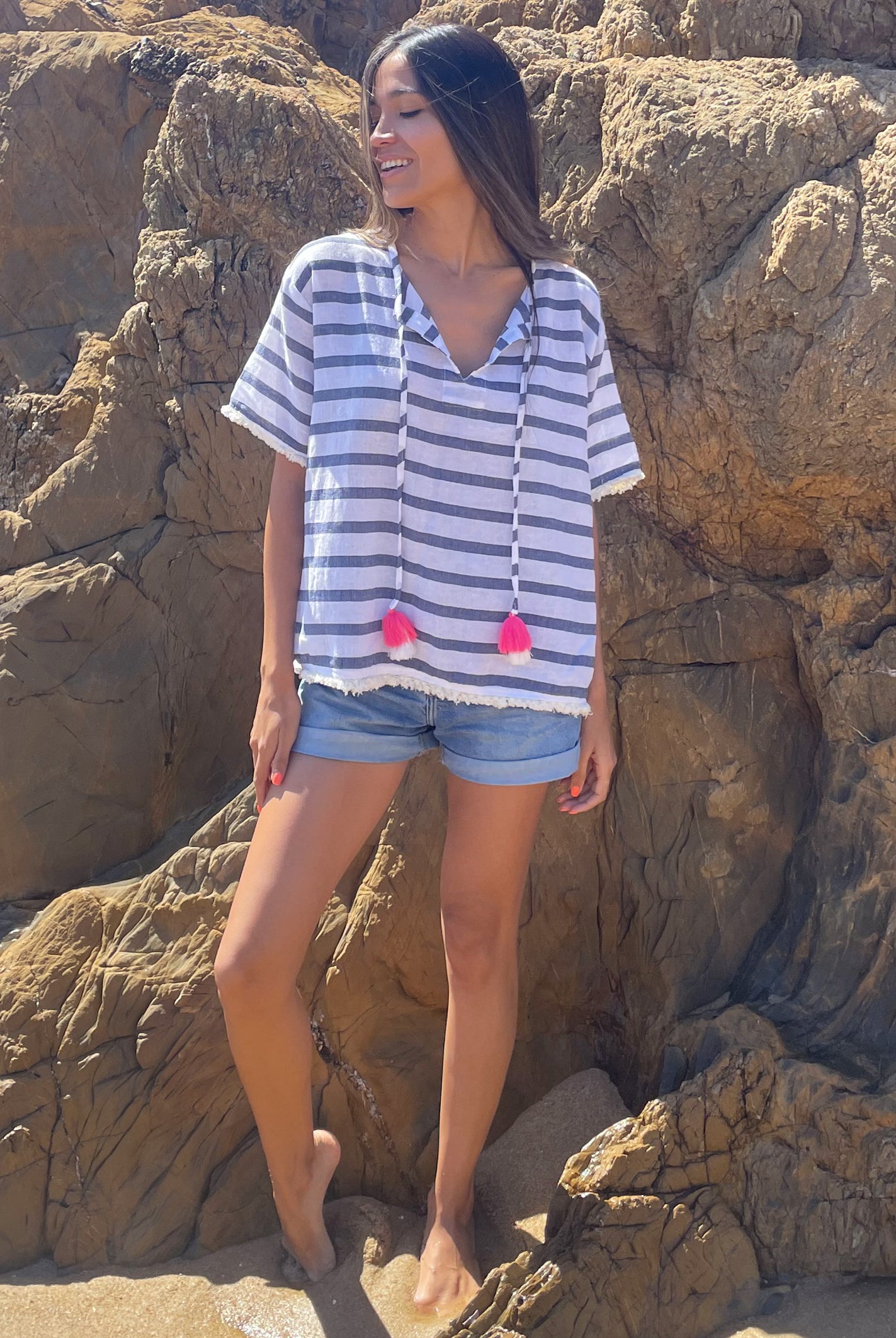 A model stood on a beach wearing a Rosebud by Rose and Rose Antibes top and denim cut off shorts. 