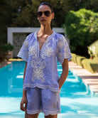 Woman wearing a blue striped Azalea blouse and matching short by a poolside