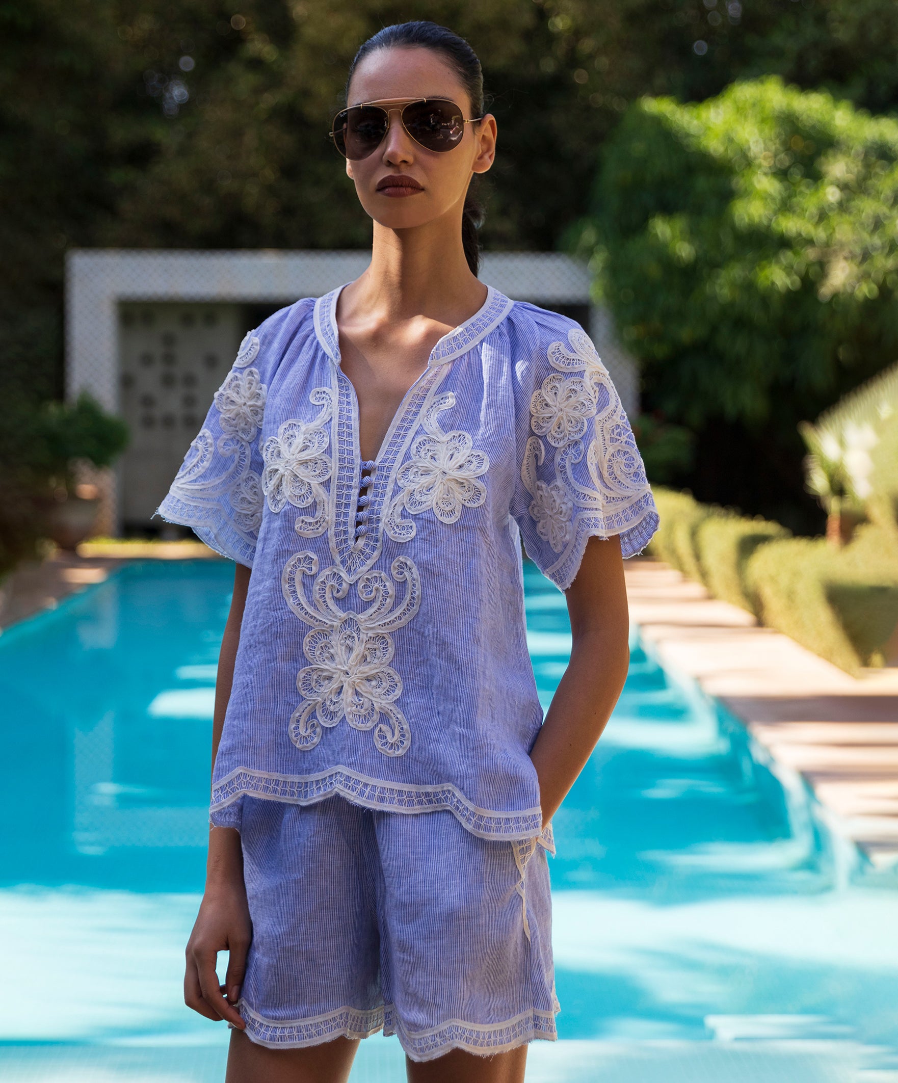 Woman wearing a blue striped Azalea blouse and matching short by a poolside