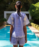 Woman wearing a blue striped Azalea blouse and matching short by a poolside