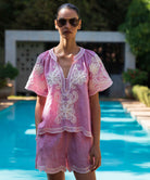 Woman wearing a red striped Azalea embroidered blouse with matching shorts by a pool