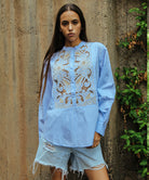 A model wearing a Rose and Rose Barbican embroidered shirt in blue cotton. 