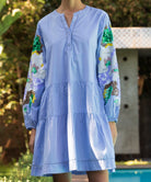 Light blue Beech dress with sequins in floral patterns on sleeves, worn in garden.