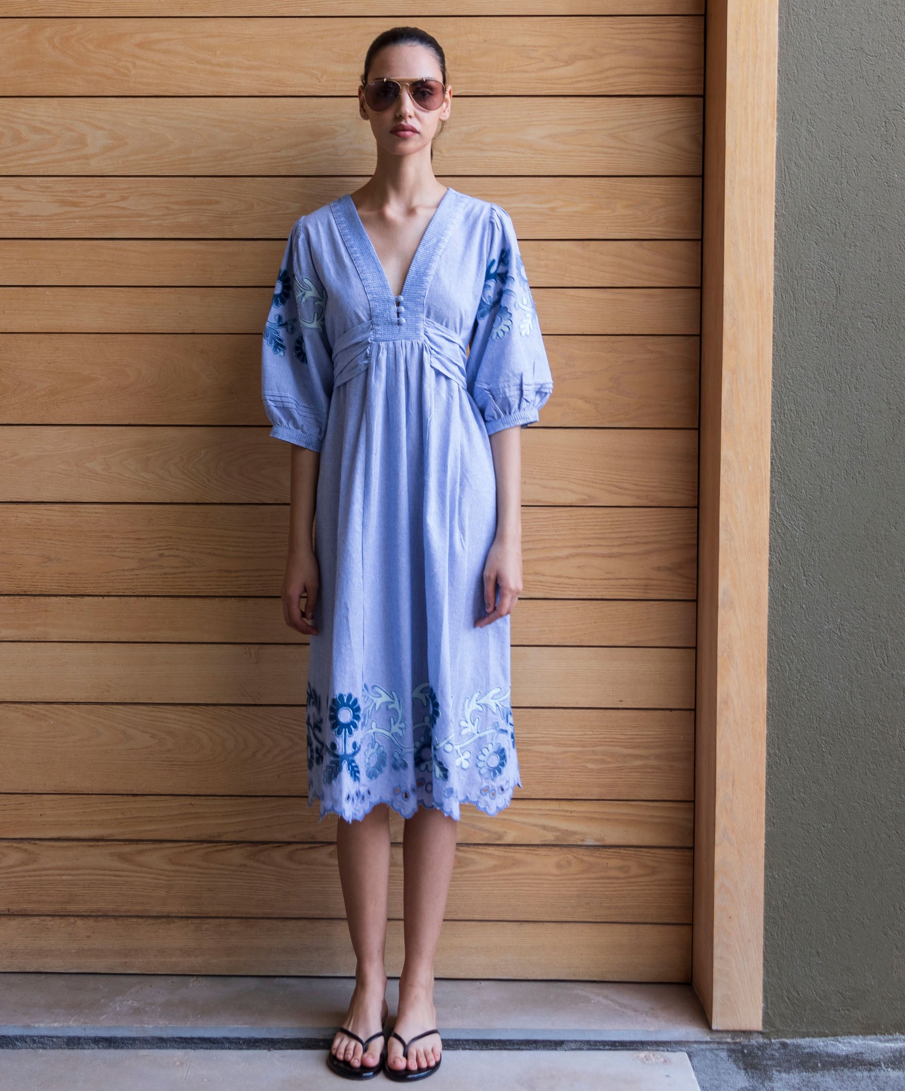 Woman wearing a blue striped Begonia dress with denim applique decoration and embroidery.