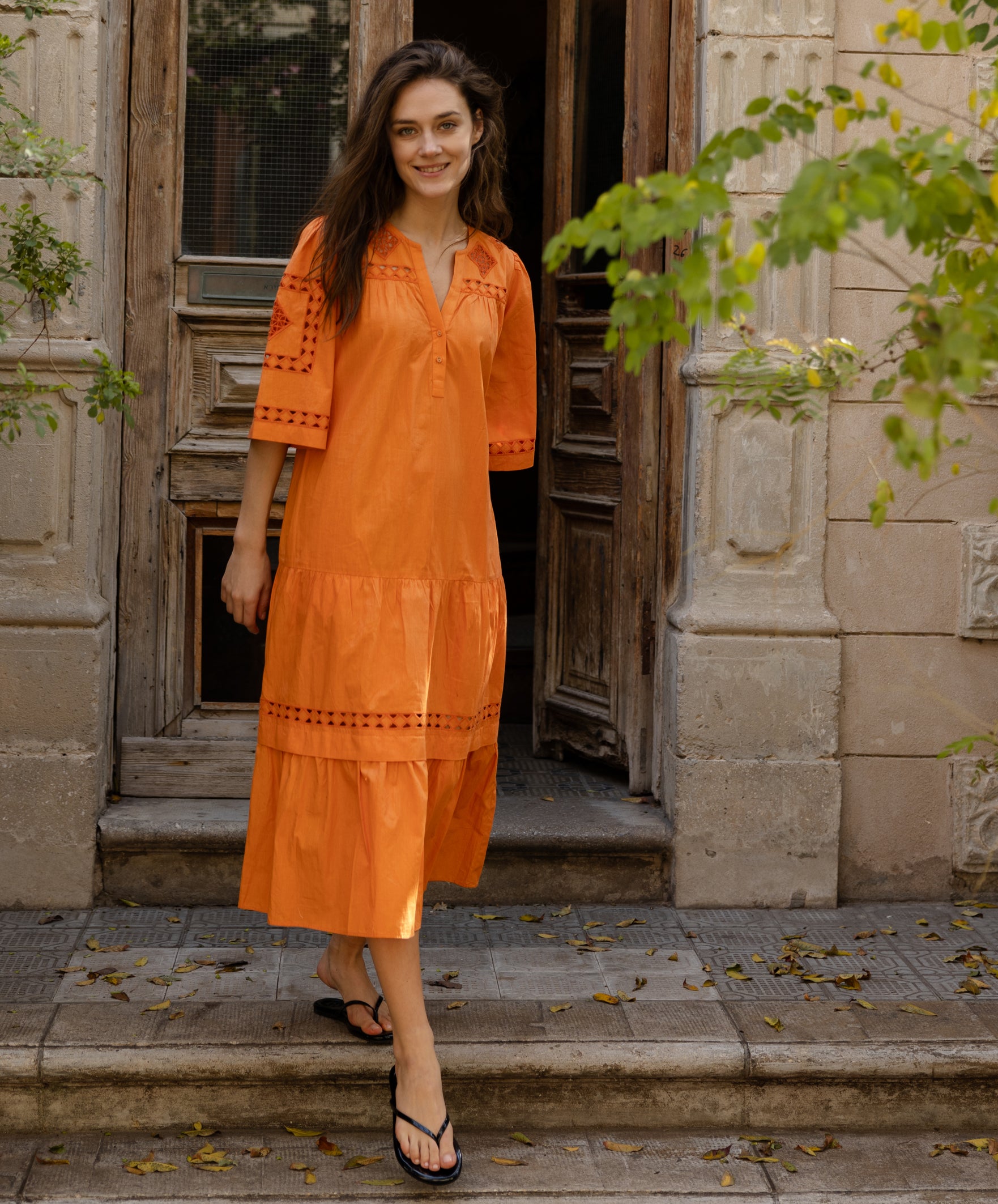 A model wears a Rose and Rose embroidered Biarritz dress in saffron orange cotton. 