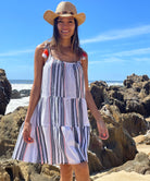 A close up of a model on a beach wearing a Rosebud by Rose and Rose Biarritz dress and straw hat.