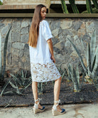 Back view of a model wearing a Rose and Rose Bond embroidered dress in white cotton. 