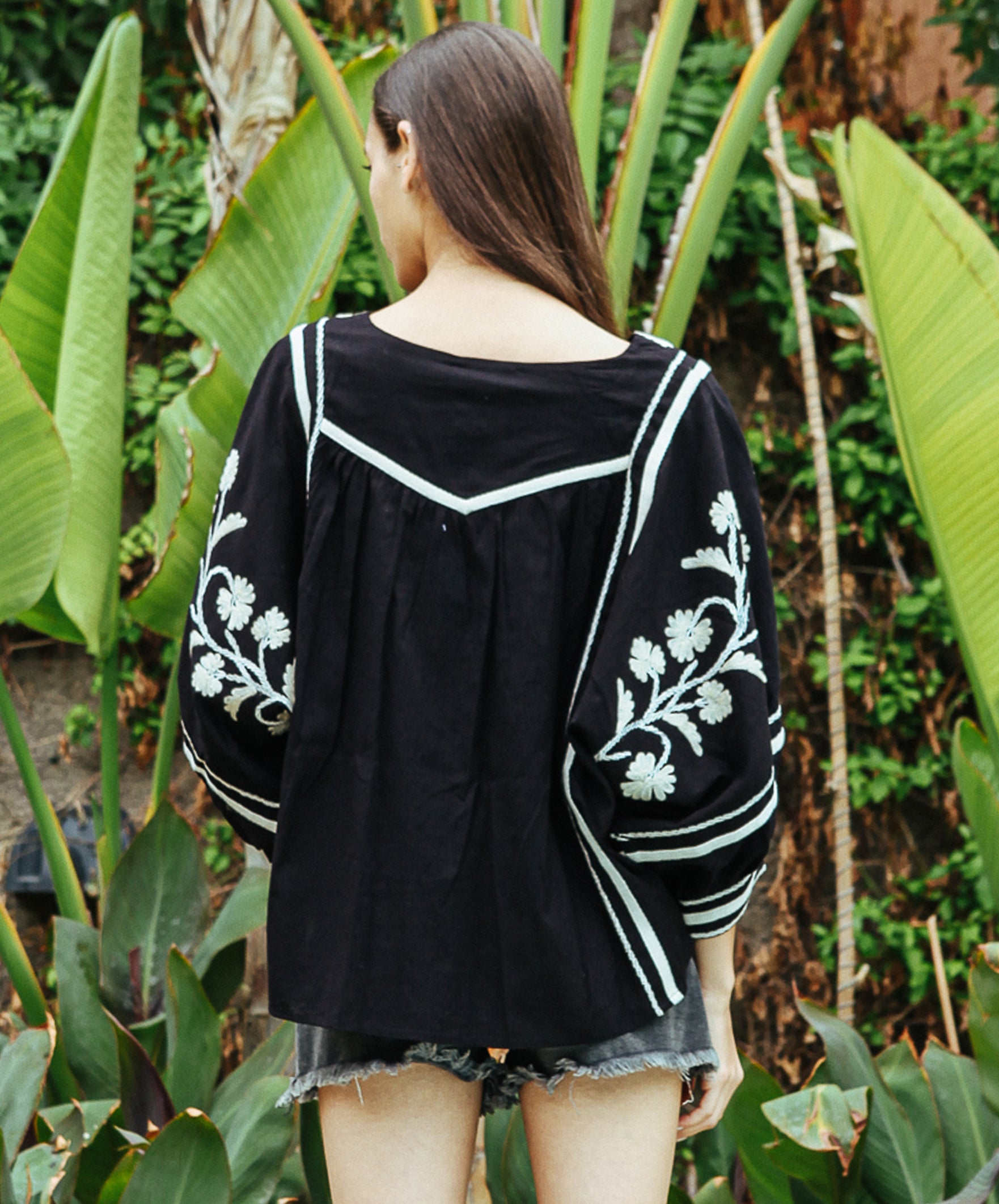 A back view of a model wearing a Rose and Rose Camden embroidered top in black cotton. 