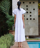 Back of a woman in a white Camelia dress standing by a pool.