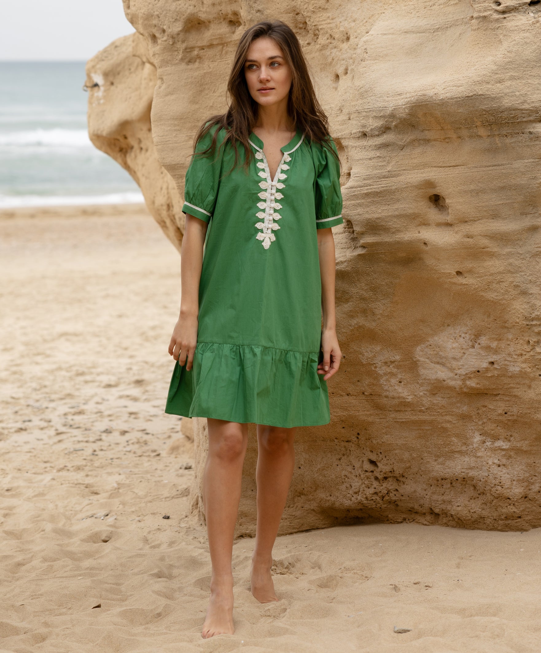 A model wearing a Rose and Rose green cotton Cannes dress with passementerie decoration. 