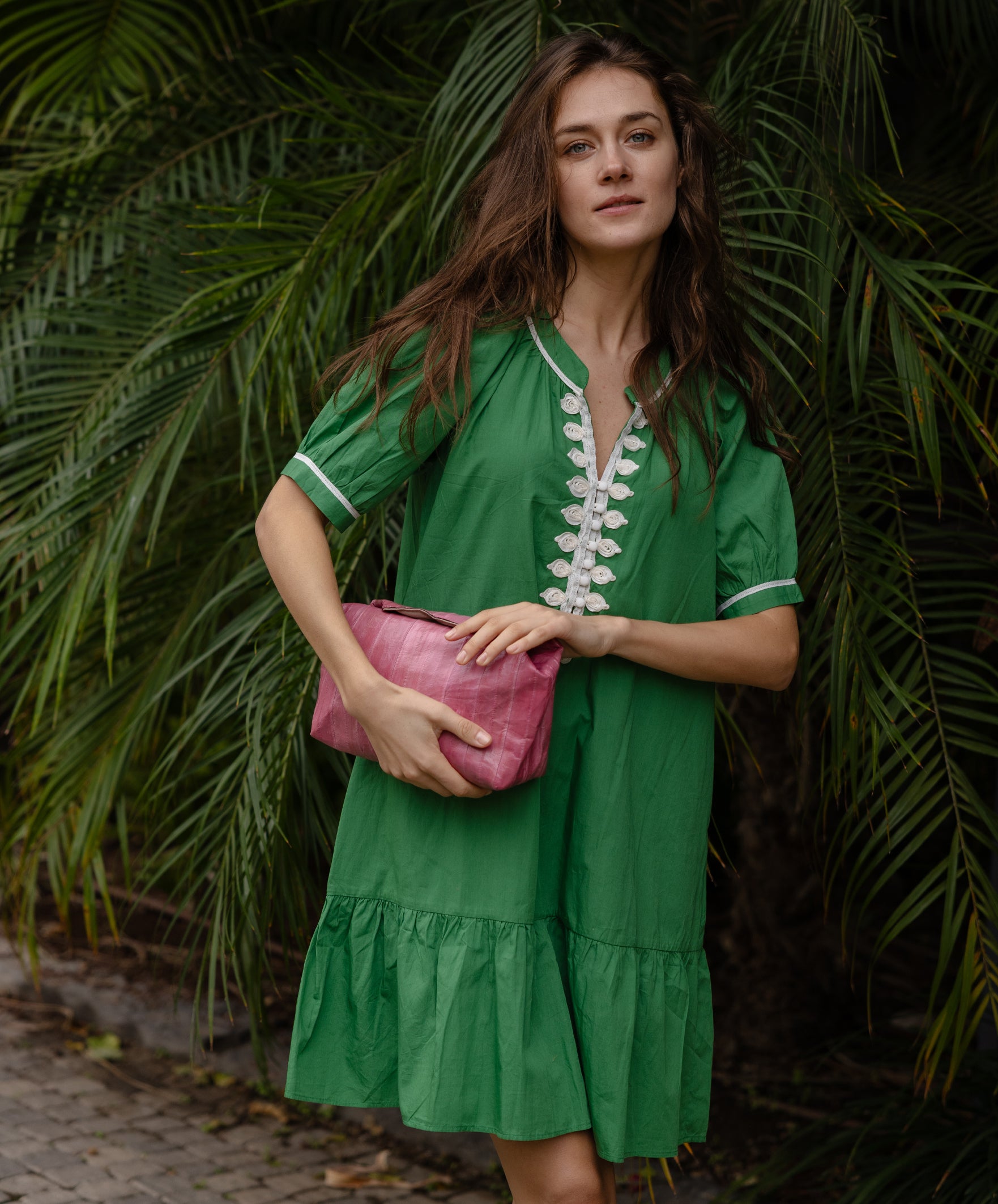 A model wearing a Rose and Rose green cotton Cannes dress with passementerie decoration. 