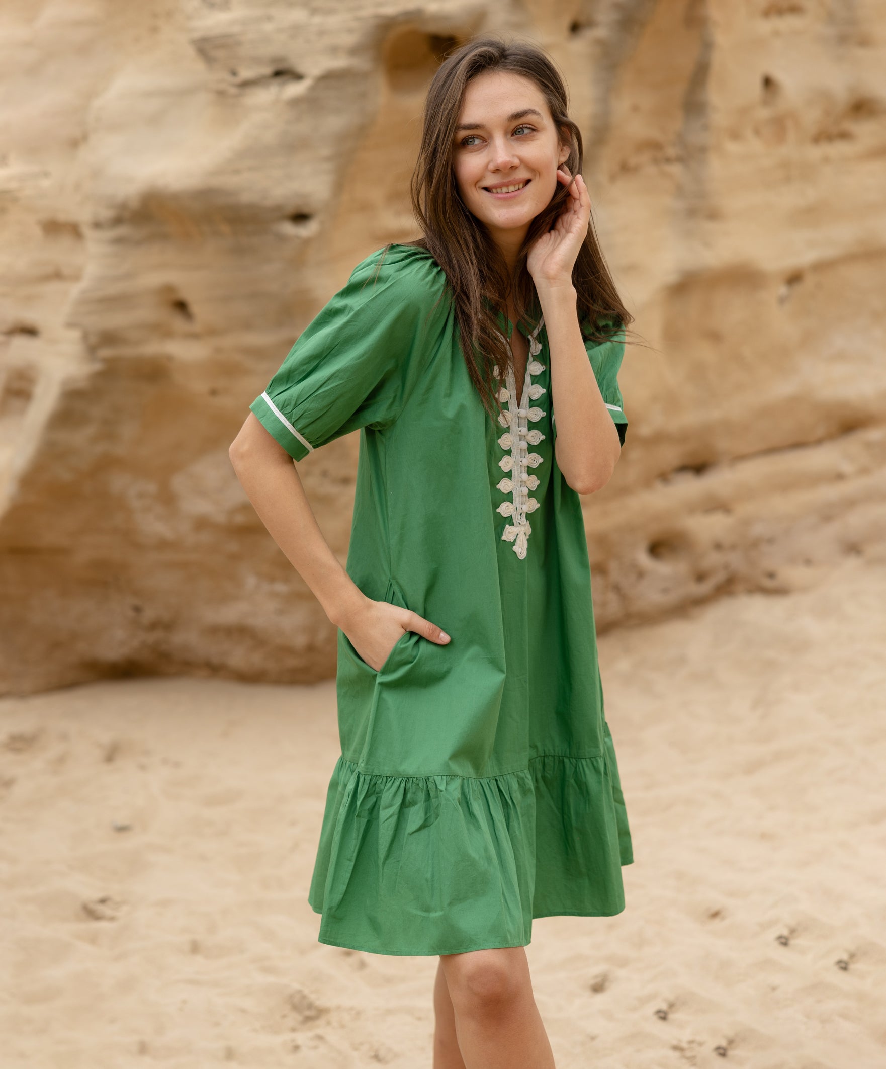 A model wearing a Rose and Rose green cotton Cannes dress with passementerie decoration. 