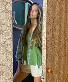 A model opening a door wearing the Rose and Rose Capri embroidered top in olive cotton.