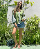 A model in a garden wearing the Rose and Rose Capri embroidered top in olive cotton.