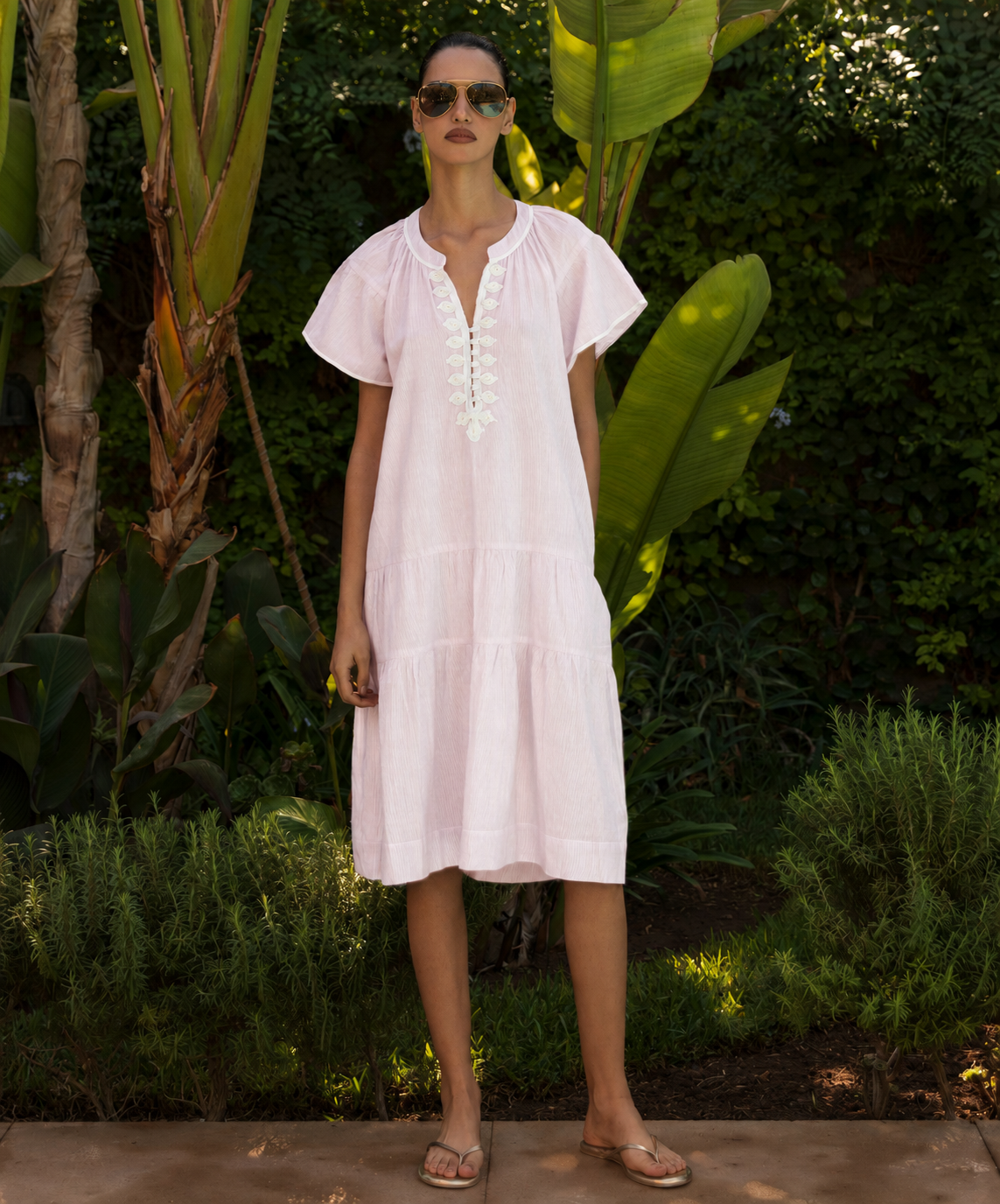 Woman wearing a light pink dress standing in a garden setting
