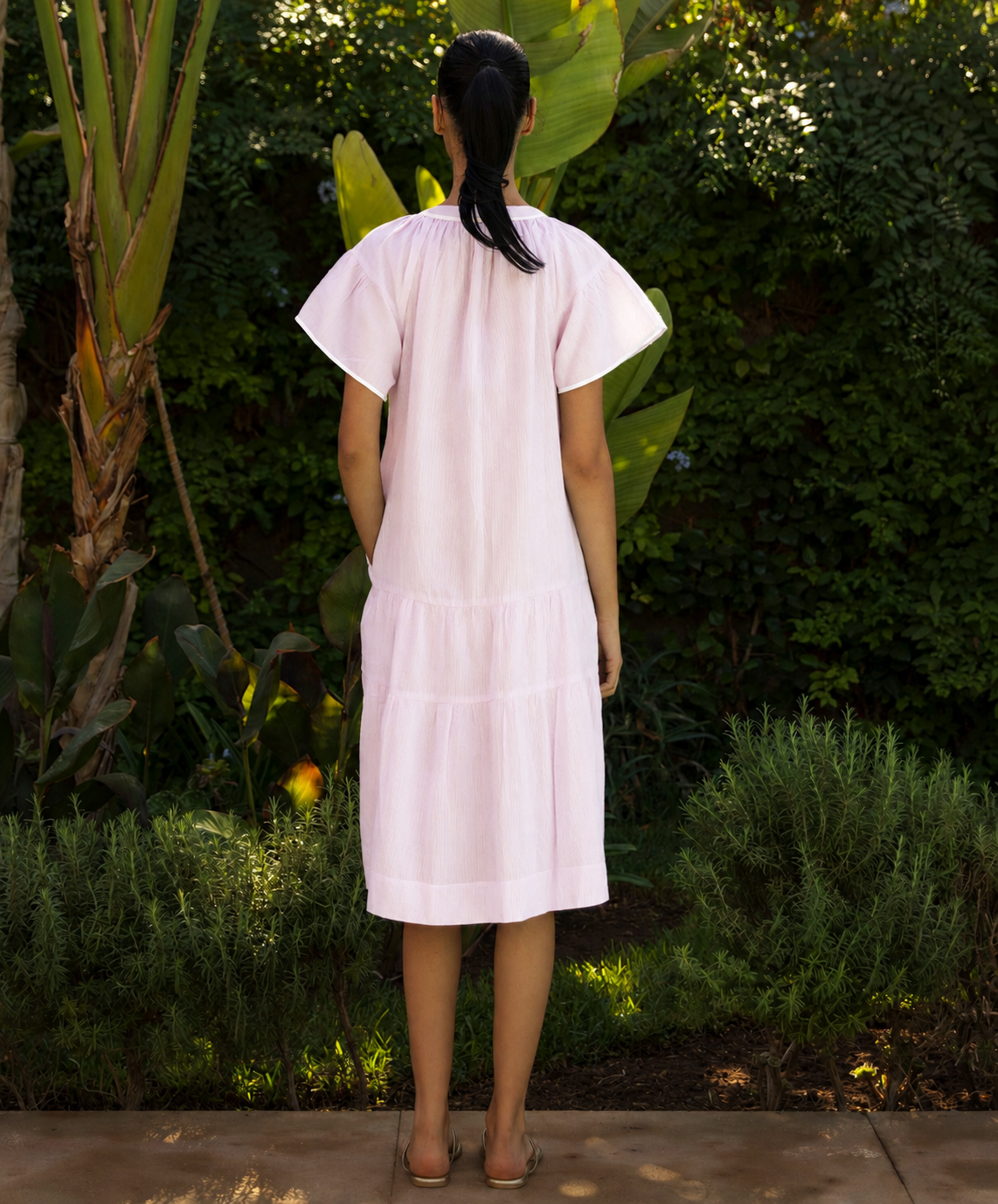 Woman wearing a light pink dress standing in a garden setting
