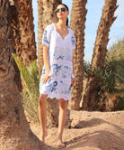 Woman in a floral applique decorated Cedar white dress standing among palm trees in a desert setting