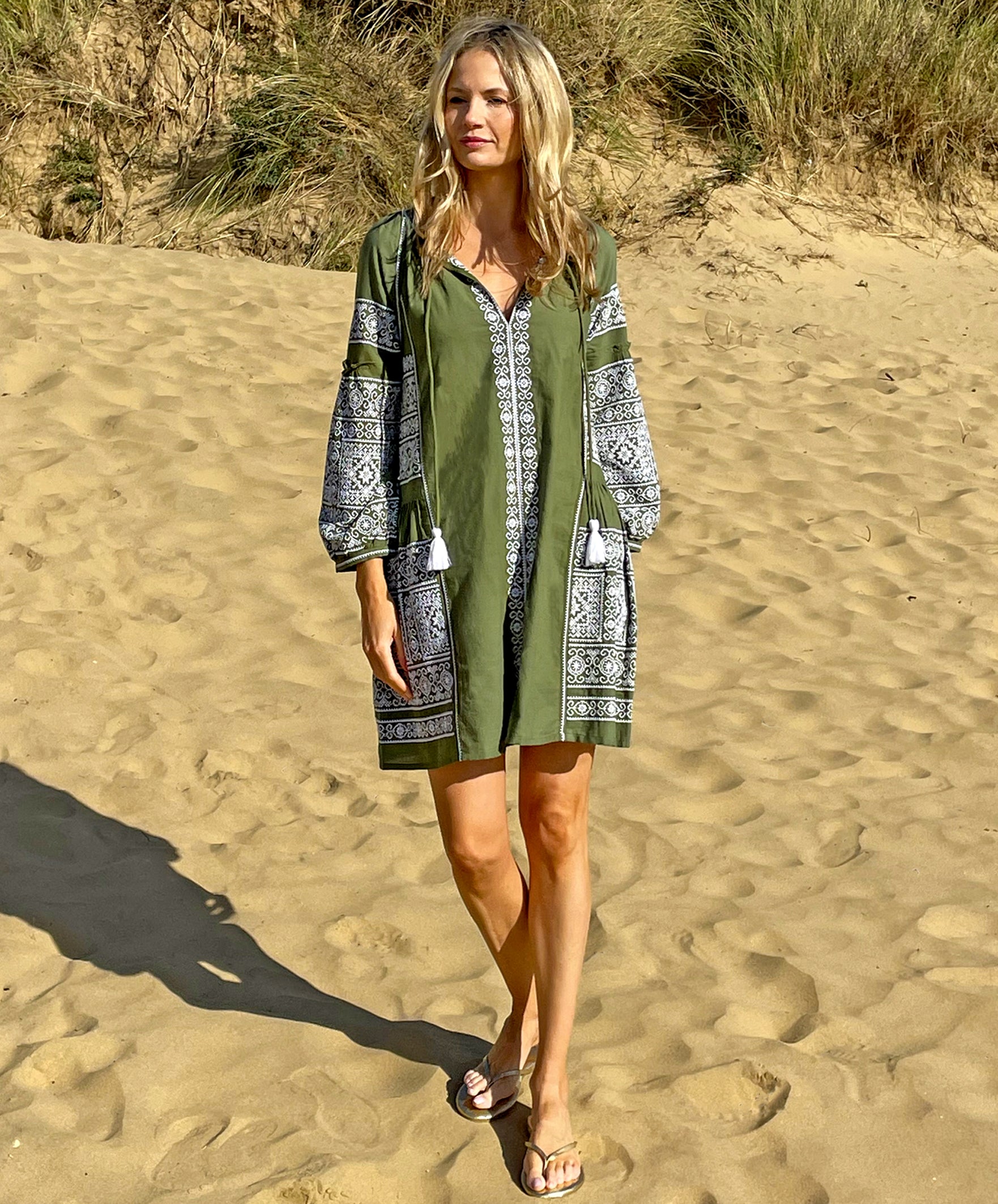 A model on a beach wearing the Rose and Rose Como embroidered dress in olive cotton.