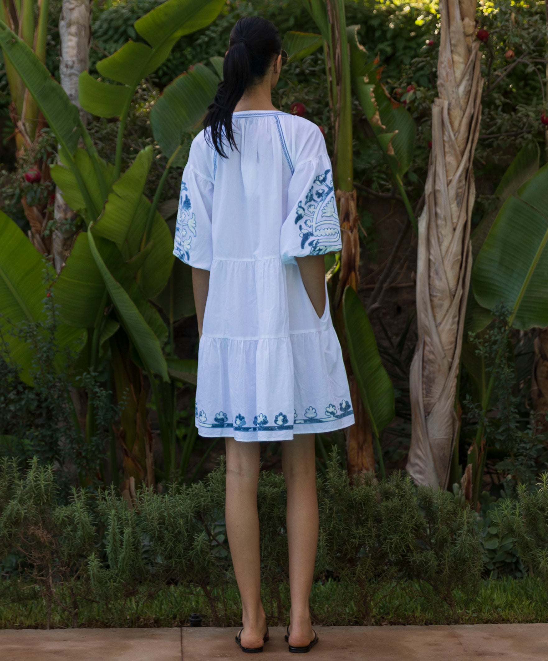 Back View of a woman wearing a white Cypress dress standing in a tropical garden setting