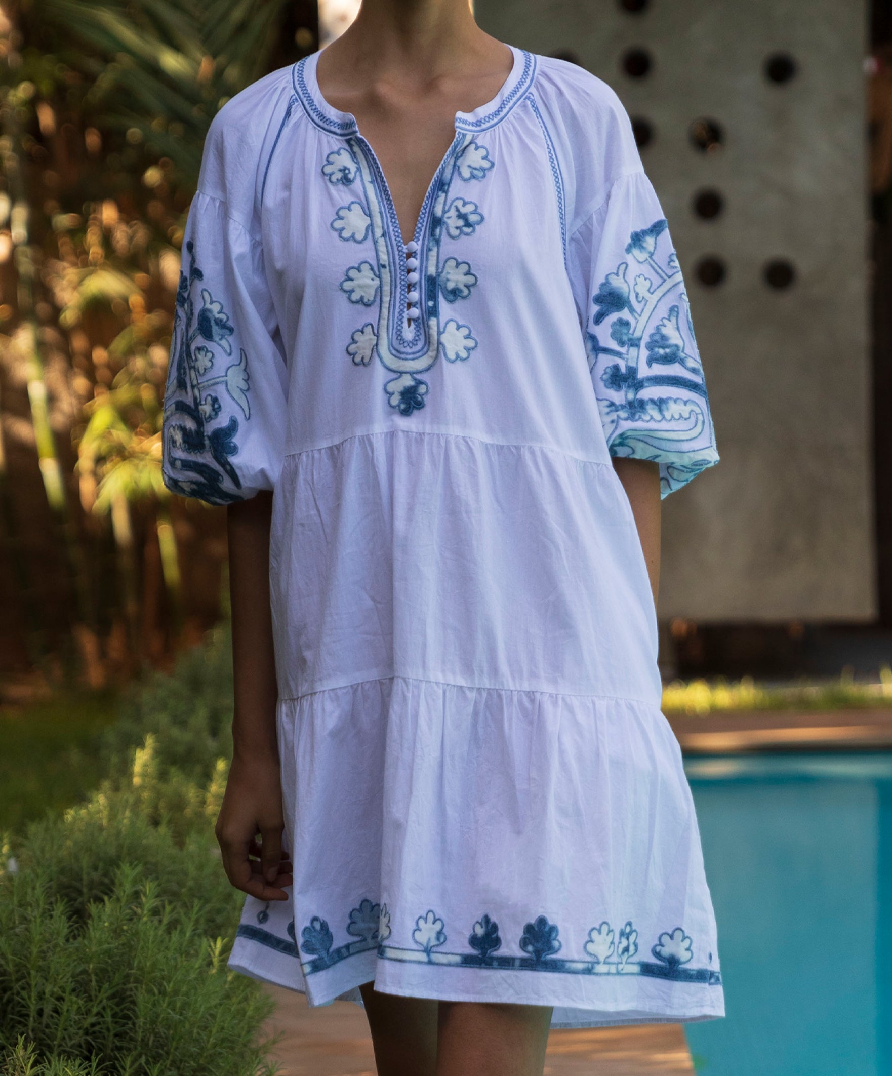 Close up photo of a woman wearing the white Cypress dress with denim applique