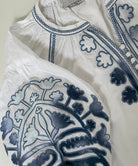 White dress with blue embroidery on a light gray background
