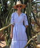 Woman in a light blue Dahlia dress and straw hat standing among cacti