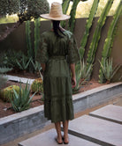 Woman wearing a green embroidered dress and straw hat standing in front of cacti