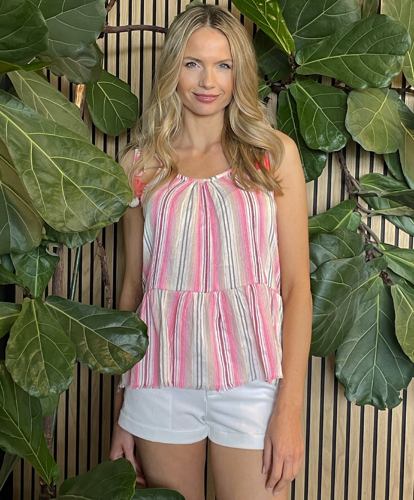 A model wearing a Rosebud by Rose and Rose pink Mexican striped camisole top with tasselled tie straps. 