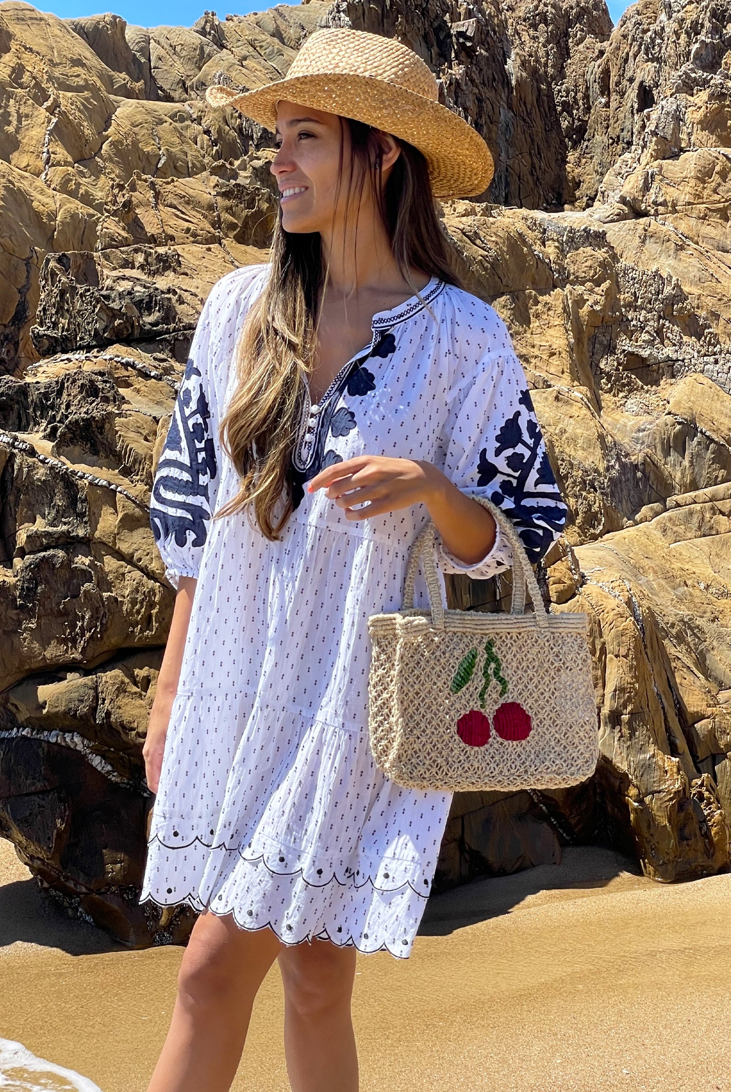 A model wearing a Rose and Rose white Firenze dress and holding a jute bag by The Jacksons. 