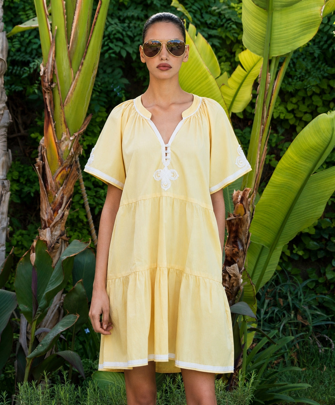 Woman in a yellow dress standing among tropical plants