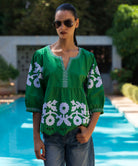 Woman wearing a green blouse with white floral patterns by a pool