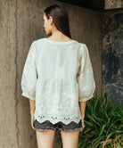 Back view of a model wearing a Rose and Rose Goldhawk decorated top in natural linen. 